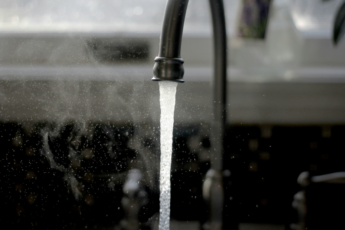 A black and white image of a running water faucet