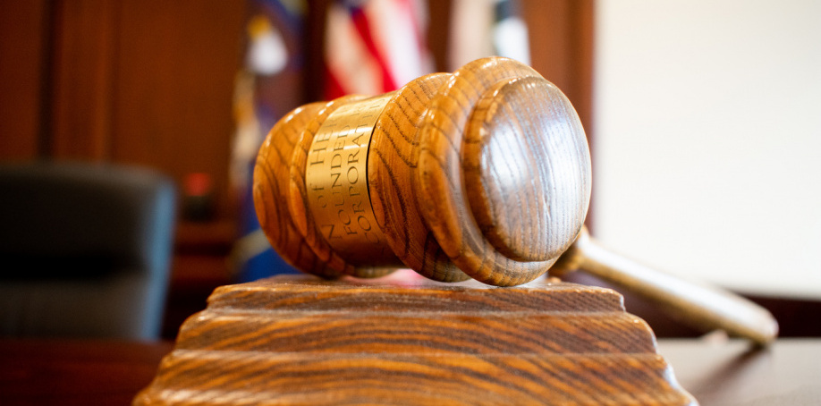 Close up image of the Herriman Justice Court gavel with flags in the background.