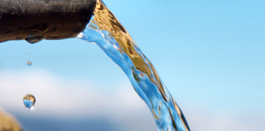 Water pours out of a metal pipe