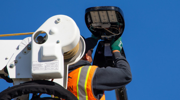 A City employee in a bucket truck repairs a broken street light